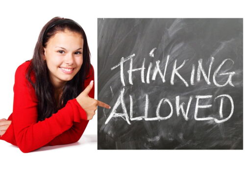 Ein Mädchen zeigt auf eine Tafel mit dem Text "thinking allowed"