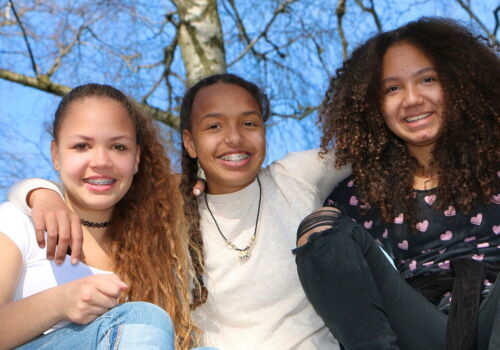 drei lachende Mädchen vor Baum